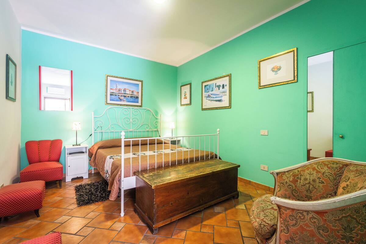 A bedroom with a bed, a chair, a dresser, and a mirror.