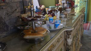 A bar area with a variety of food and drink items, a television mounted on the wall, and a decorative door with a floral pattern. - B&B Villa Felice (Giardini Naxos)