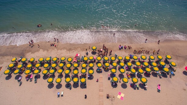 A beach with numerous sun umbrellas and beach chairs arranged in rows. - Villaggio Borgo degli Ulivi (Sellia Marina)