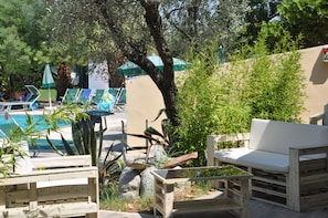 A poolside area with lounge chairs, a wooden bench, and a small table. - Villaggio Borgo degli Ulivi (Sellia Marina)