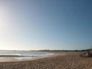 A beach with a sandy shore, waves, and a clear sky.