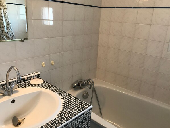A bathroom with a sink, mirror, and bathtub.
