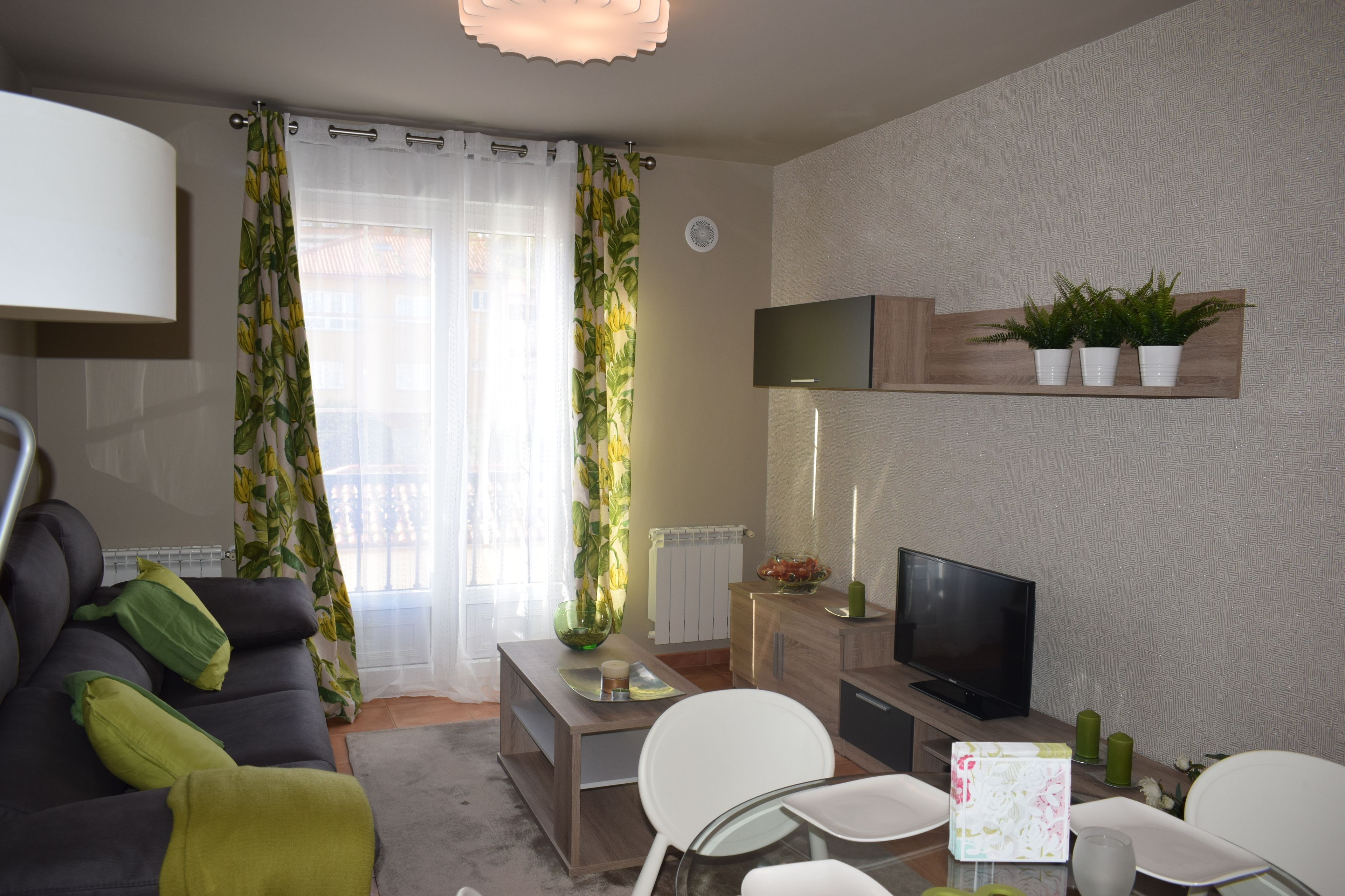 Una sala de estar con un sofá, una mesa de centro, un televisor y un comedor con sillas y una mesa.