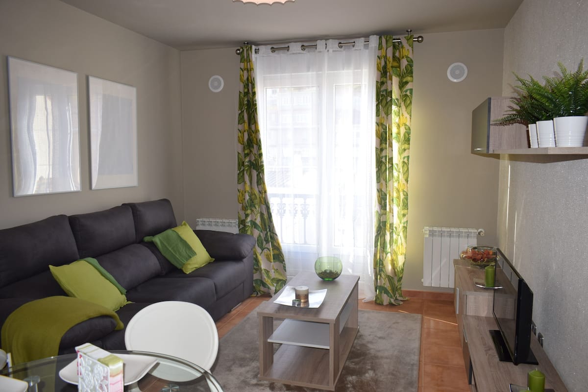 Una sala de estar con sofá, mesa de centro y mueble para televisión.
