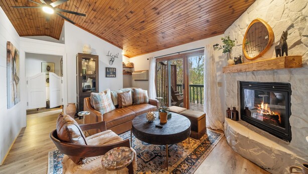 A cozy living room with a stone fireplace, wooden ceiling, and a comfortable seating area. - Vacation Cottage in Yonahlossee Resort (Boone)