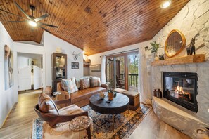 A cozy living room with a stone fireplace, wooden ceiling, and a comfortable seating area. - Vacation Cottage in Yonahlossee Resort (Boone)