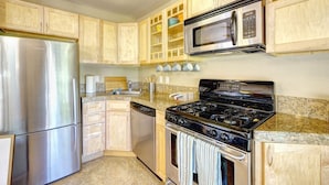 Una cocina moderna con electrodomésticos de acero inoxidable, armarios de madera y encimeras de granito.