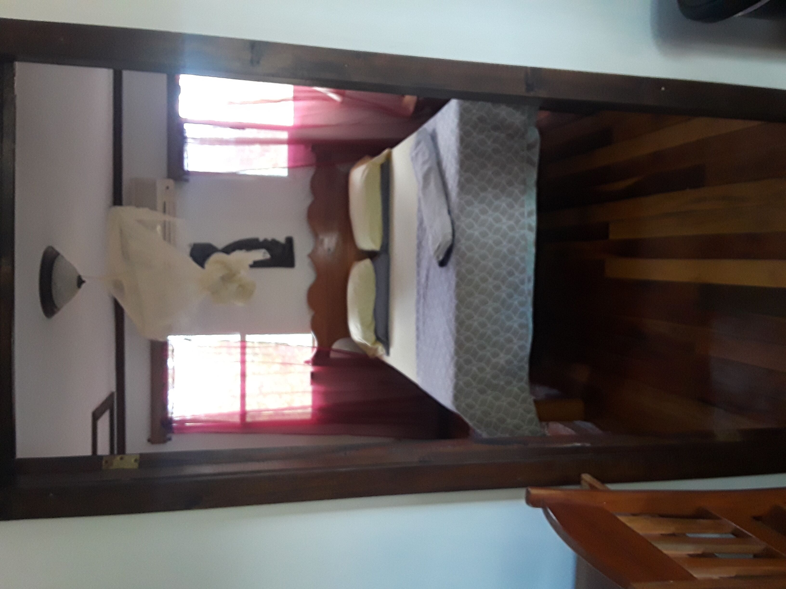 A bedroom with a bed, a window with curtains, and a wooden staircase.