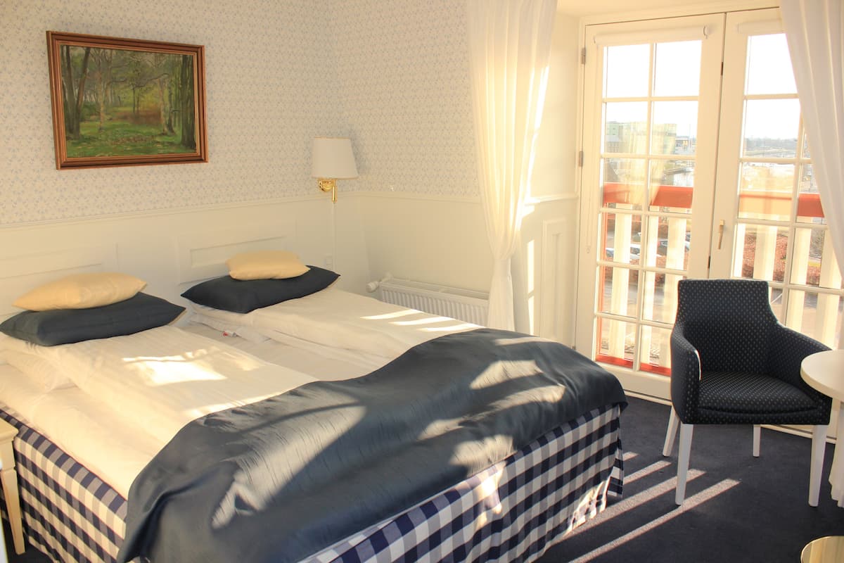Una habitación de hotel con cama, una silla y una ventana con vista a edificios.