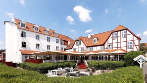 Un hotel de estilo europeo tradicional con varias edificaciones, un patio central con asientos y una fuente.