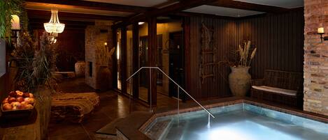 A spa area with a hot tub, wooden benches, and a staircase leading to a room with a large window.
