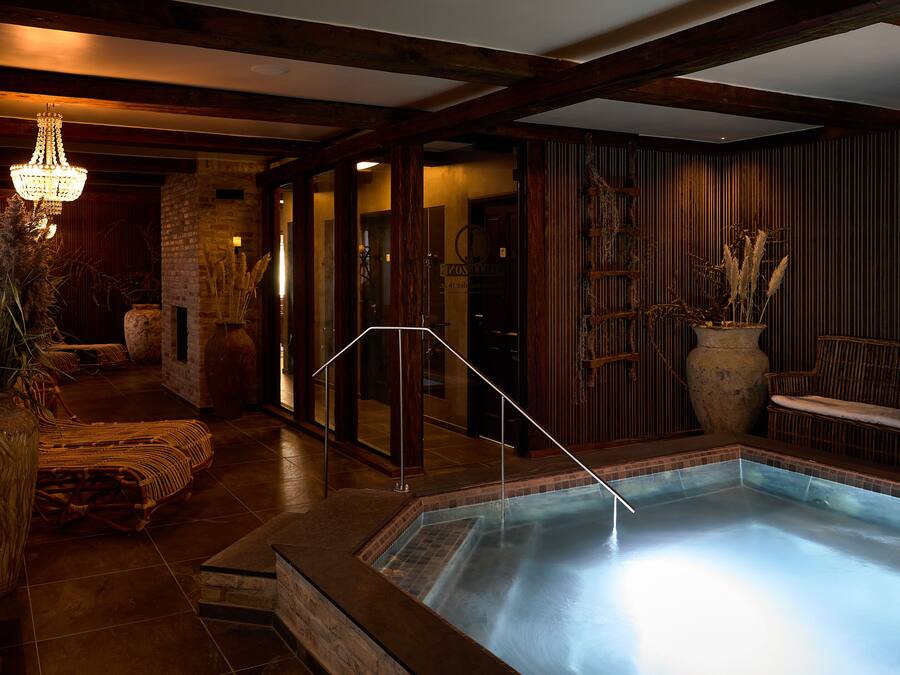 Área de spa com hidromassagem, bancos de madeira e escada que leva a um quarto com uma grande janela.