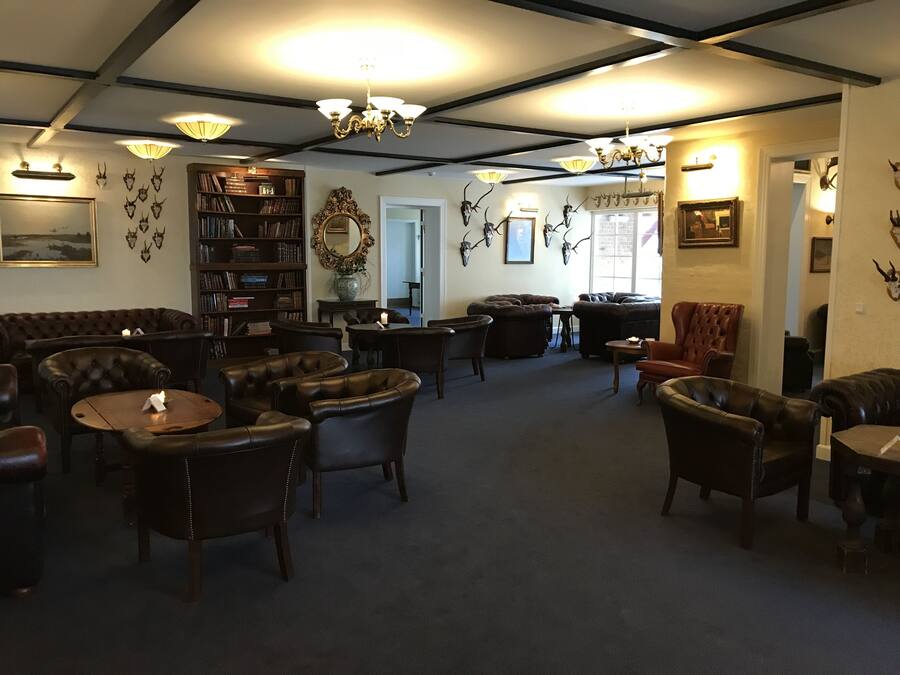 A cozy, well-lit room with leather furniture, a bookshelf, and decorative antler wall art.