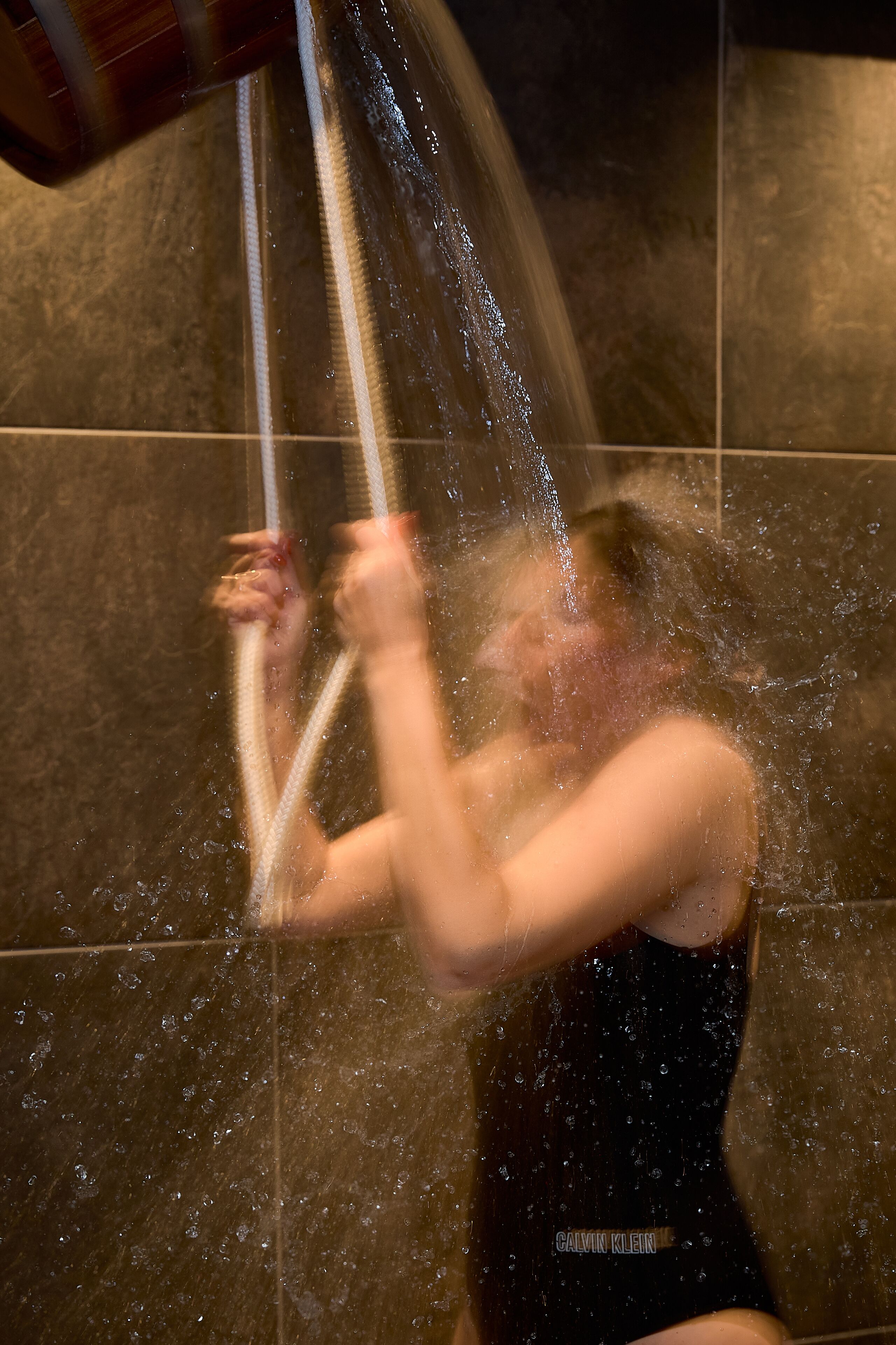 A person in a bathtub with water flowing from a showerhead.