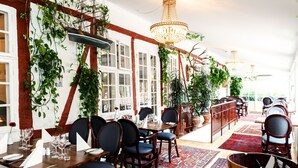 Un restaurante con mesas y sillas de madera y plantas colgantes.