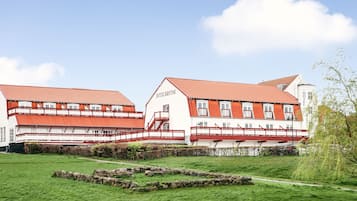 A two-story hotel with a red-tiled roof and white walls, featuring a central staircase and multiple balconies.