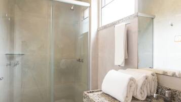 Een moderne badkamer met een douchecabine van glas, een wit toilet en een wastafel met granieten blad.