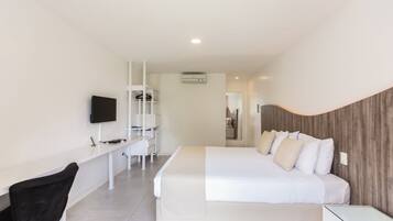 A modern hotel room with a large bed, a desk with a chair, a television, and a wardrobe.