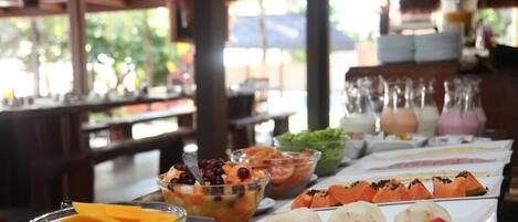 A buffet table with various fruits and dishes.