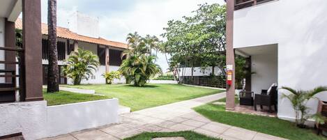 A courtyard with a tiled pathway, palm trees, and outdoor seating.