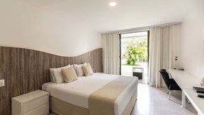 A modern hotel room with a large bed, a desk, and a view of greenery outside. - Duro Beach Garden Hotel (Caucaia)
