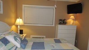 A bedroom with a bed, a nightstand, a lamp, a dresser, and a television mounted on the wall. - Updated Spectacular Kitchen Great Ocean Views Bikes & Beach Gear included (Hilton Head Island)