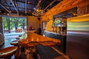 Un interior rústico de madera con una barra, un refrigerador y vistas al exterior.