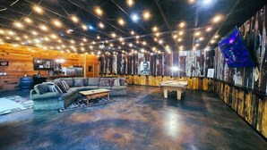 Uma sala de estar moderna com parede de madeira, um sofá, uma mesa de centro e uma mesa de bilhar.