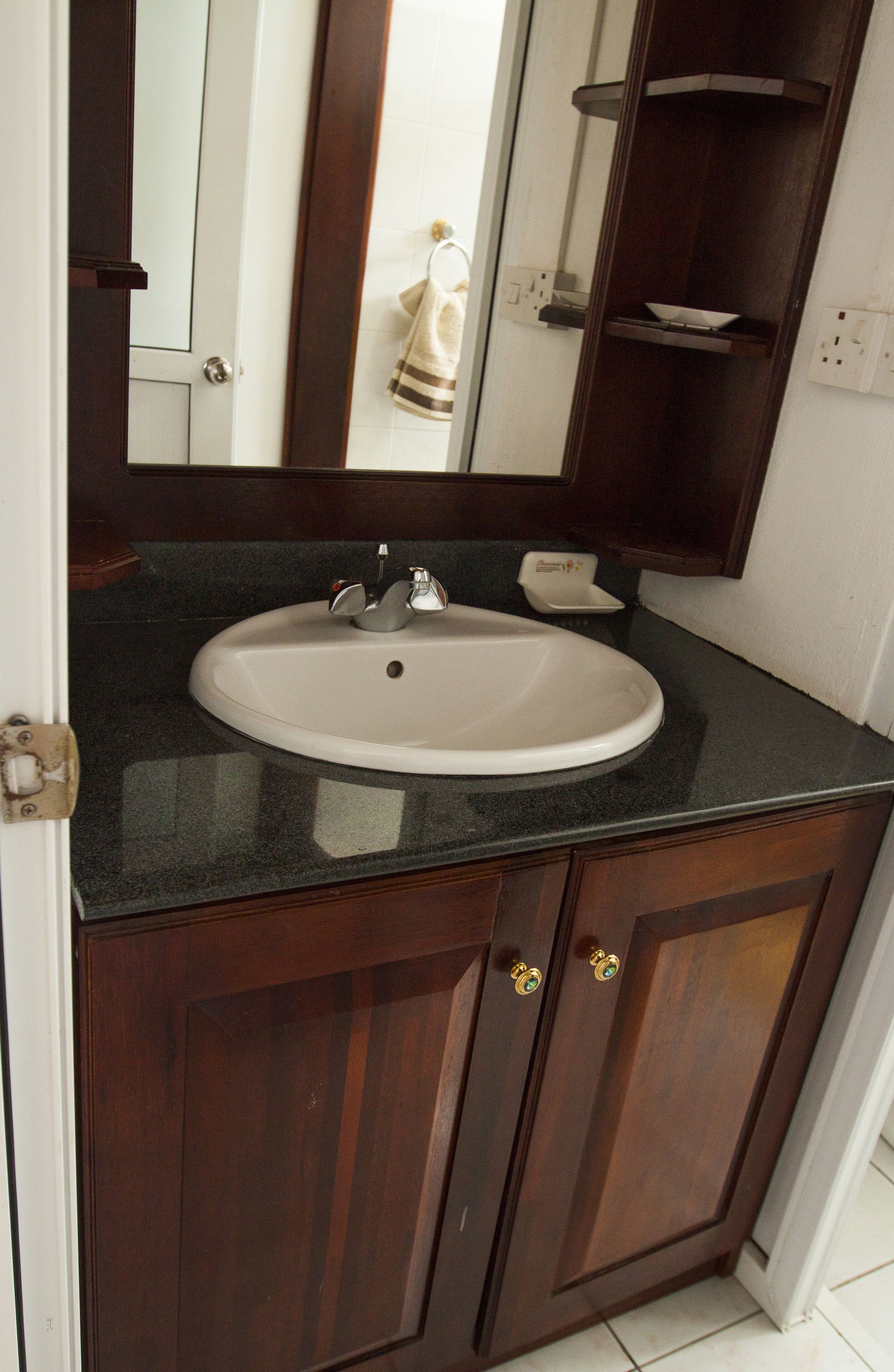 A bathroom with a white sink, dark wooden vanity, and a mirror above the sink.