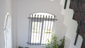 A staircase with metal railings, a window with metal bars, and two potted plants. - The Impala Mauritius Holiday Rentals (Mont Choisy)