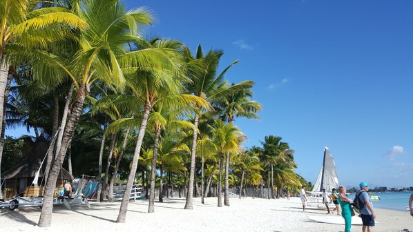 Una playa cerca, arena blanca, sillas reclinables de playa, sombrillas