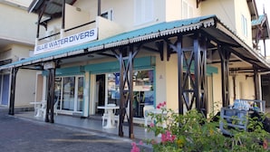 A building with a sign reading "BLUE WATER DIVERS" and a covered outdoor seating area with white plastic chairs. - The Impala Mauritius Holiday Rentals (Mont Choisy)