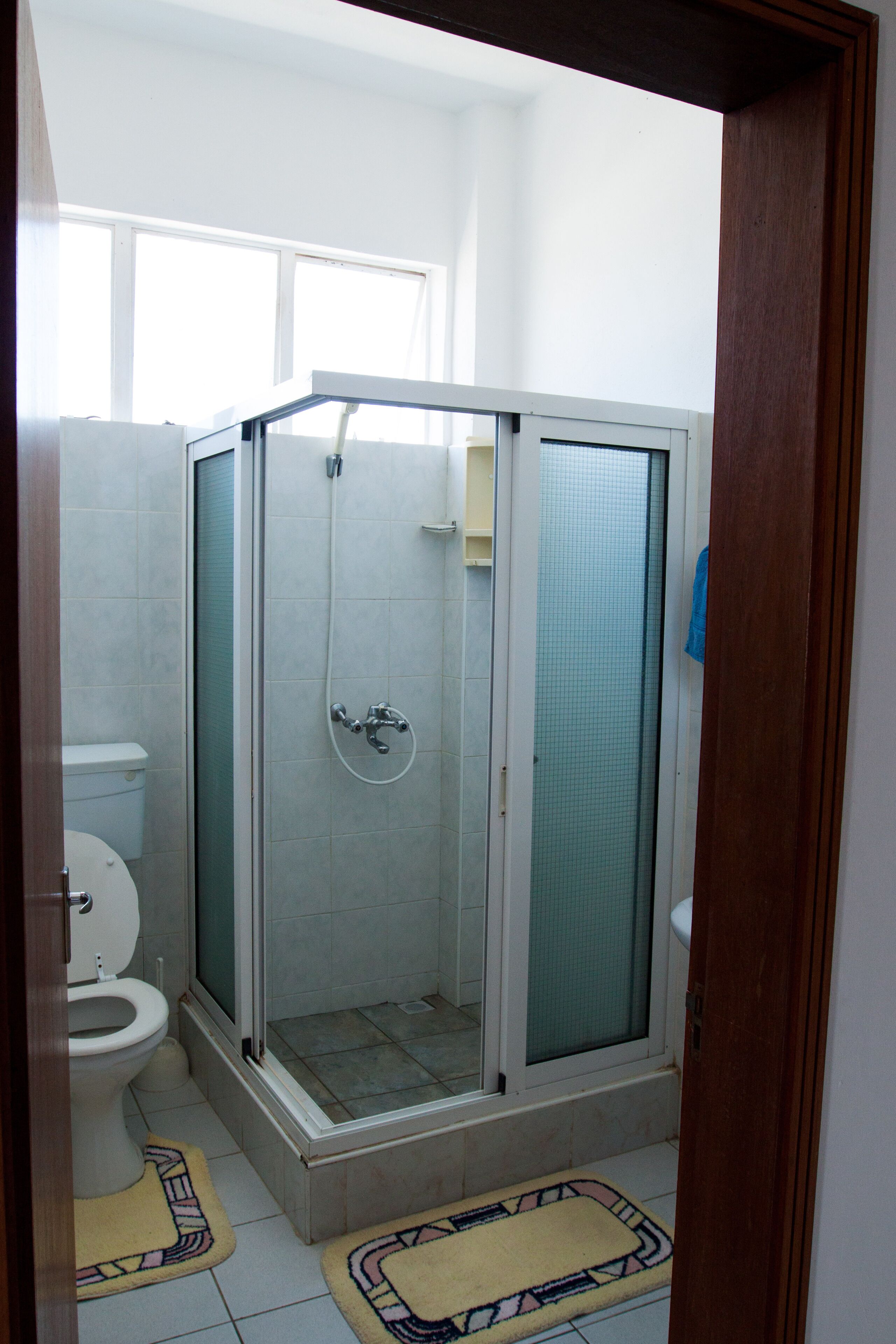 A bathroom with a glass-enclosed shower, a toilet, and a sink.