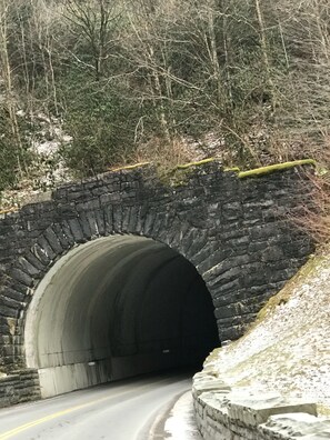 A stone bridge over a road with a tunnel entrance.