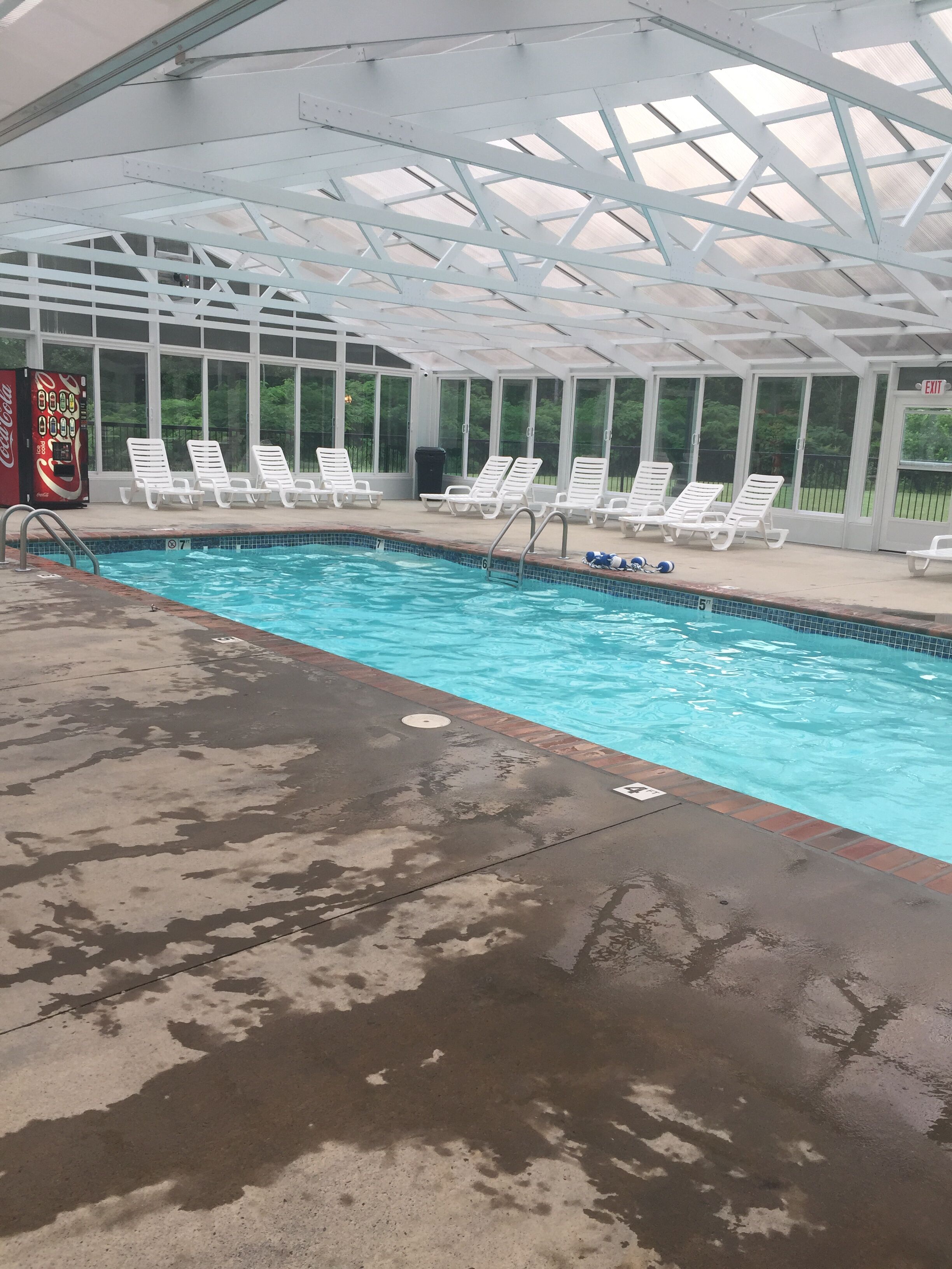 Una piscina interior amb gandules blanques i una màquina expenedora de Coca-Cola.