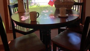 A round wooden table with four chairs, a vase with flowers, a basket, and a sign that reads "Welcome to our home." - Charming, Cozy, Cottage. Location Perfect for Outdoor enthusiasts and Couples (South Lake Tahoe)