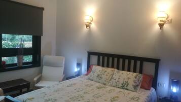 Une chambre à coucher comprenant un lit, une chaise, une table de chevet et deux lampes fixées au mur.