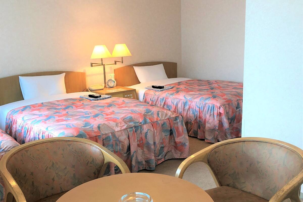Une chambre d’hôtel avec deux lits, une table et deux chaises.