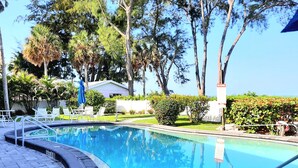 Una piscina con una profundidad de 1 metro 17, rodeada de árboles y un edificio blanco.