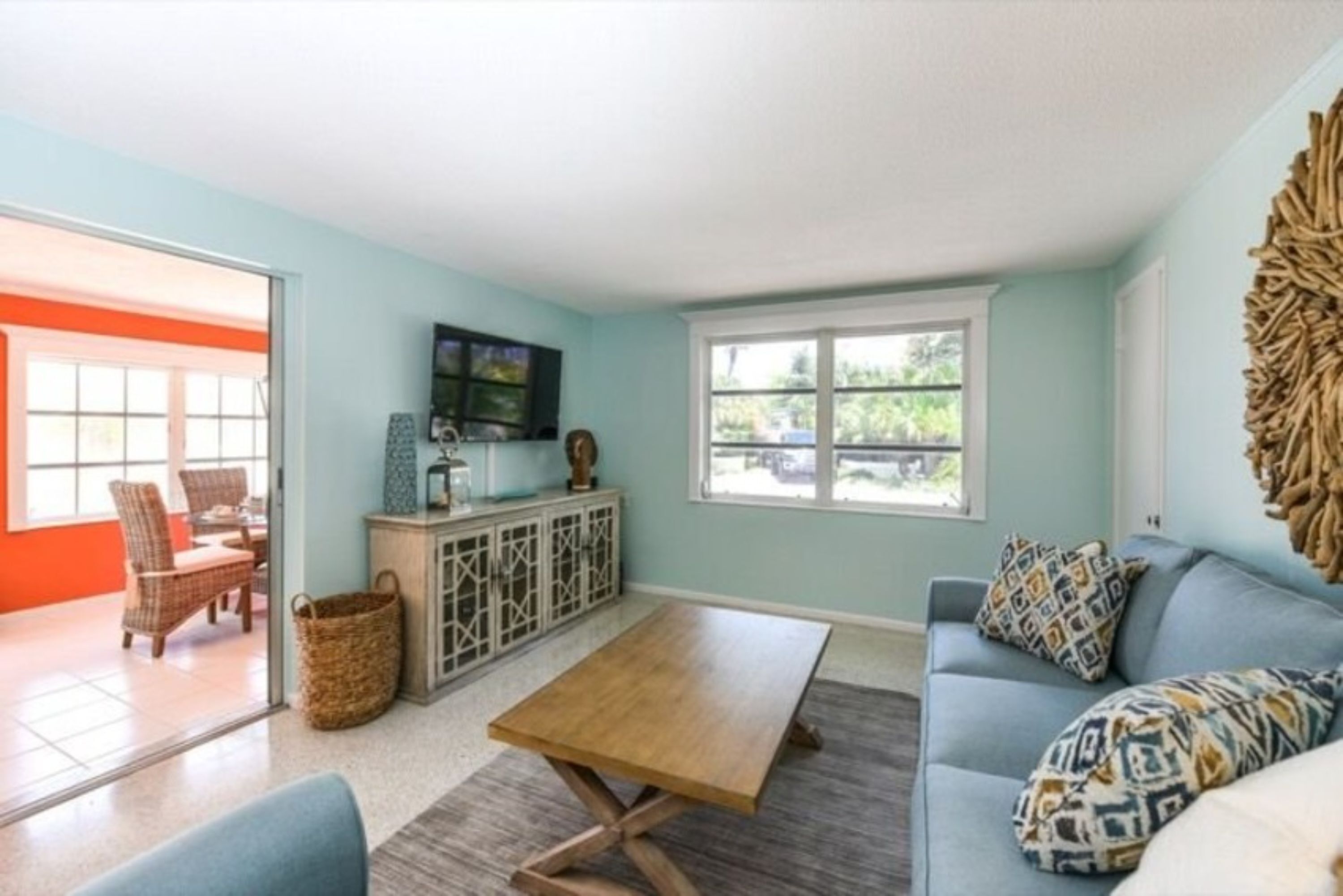 A living room with a sofa, a coffee table, a television, and a window.