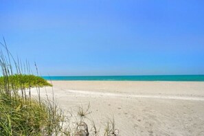 A beach with clear blue water and sandy shore. - 3706 Gulf Dr 2 Bedroom Home by RedAwning (Holmes Beach)
