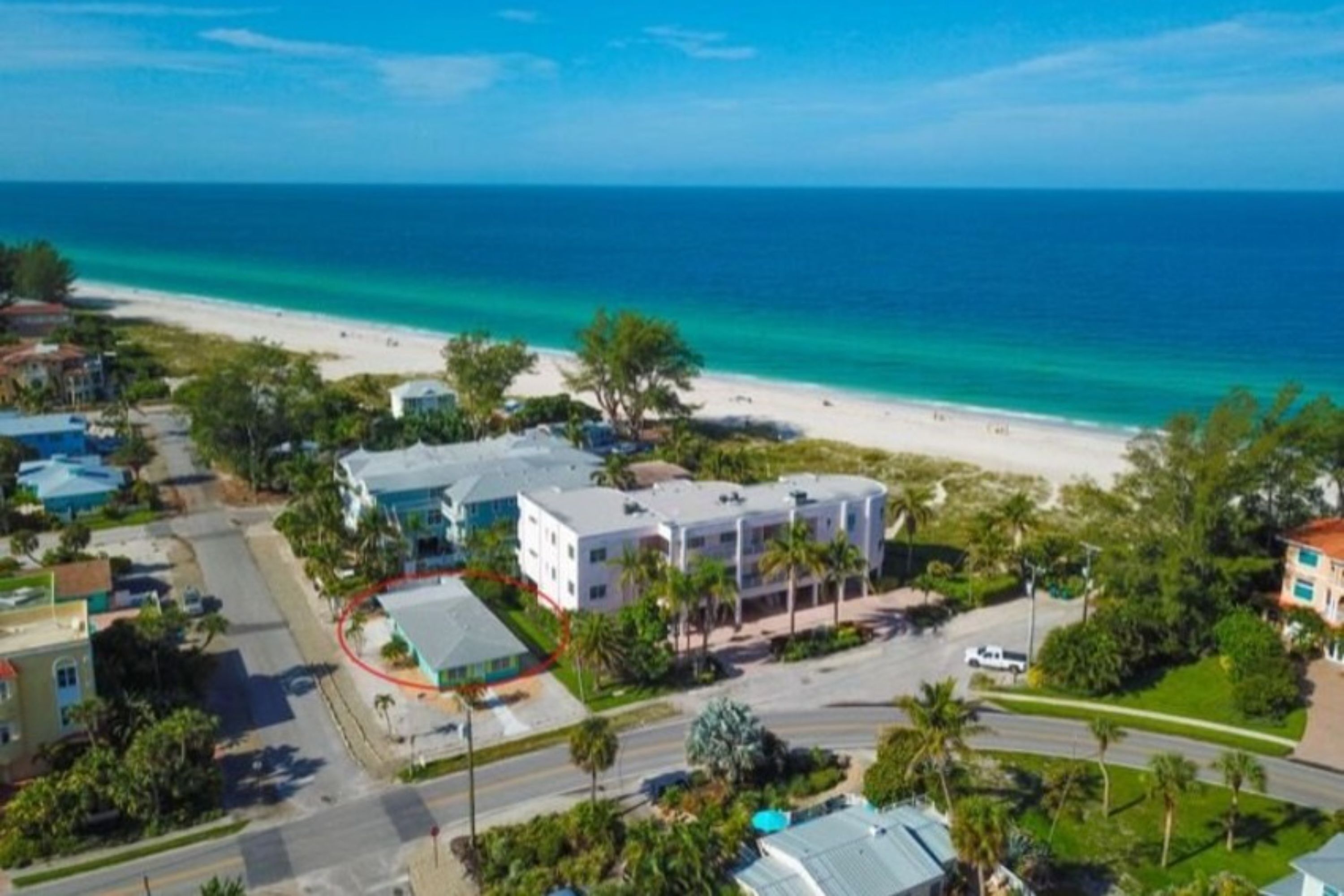 A coastal residential area with a beach, houses, and a road.