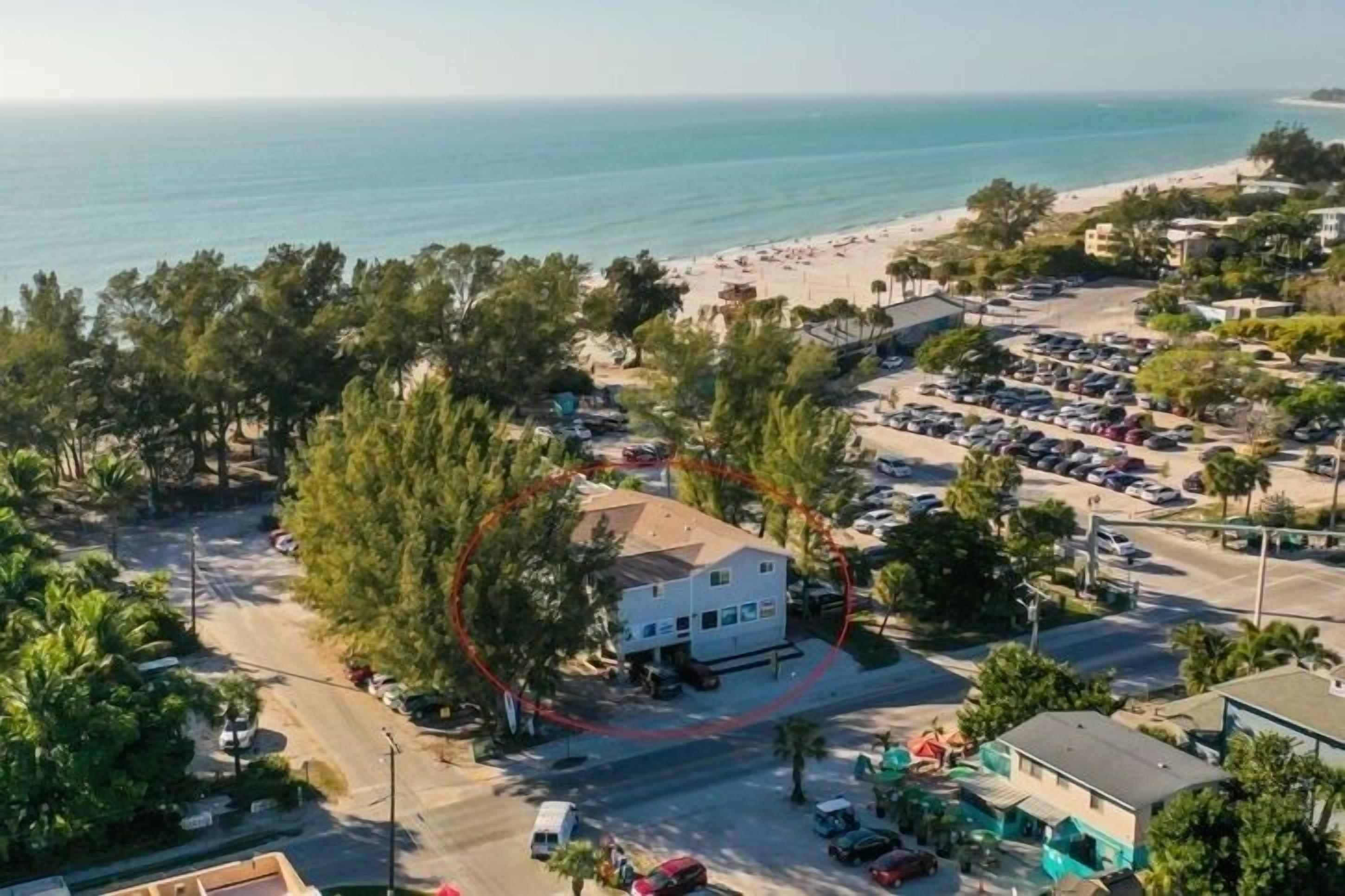 A coastal hotel with a parking lot, beach view, and a road leading to the beach.