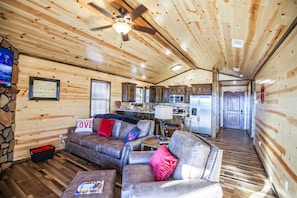 Cozy cabin-style accommodation with a comfortable sofa, TV, and kitchen area for a family-friendly stay.