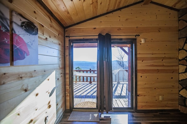 Step into this cozy cabin, featuring a wooden door, wooden ceiling, and wooden floor, with a deck view through the door.