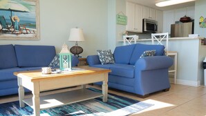 A living room with a blue sofa, a wooden coffee table, and a patterned rug. - 😎 Sun, Fun, Beach and Sand😎  FREE Beach Chairs!!  3 payments available Book now  (Panama City)