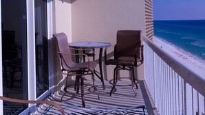 A balcony with two wicker chairs and a small round table, overlooking a beach with clear blue water and a sandy shore. - 😎 Sun, Fun, Beach and Sand😎  FREE Beach Chairs!!  3 payments available Book now  (Panama City)