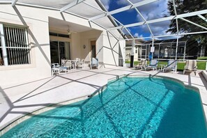 A swimming pool with clear water, surrounded by a covered patio area with lounge chairs and a building with large windows. - 134 HERST (Davenport)