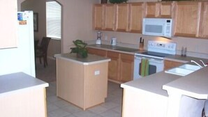 A kitchen with wooden cabinets, a microwave, a stove, and a sink. - 506 BONVILLE (Davenport)