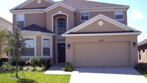 A two-story house with a garage, a front entrance, and a small front yard with plants. - 506 BONVILLE (Davenport)